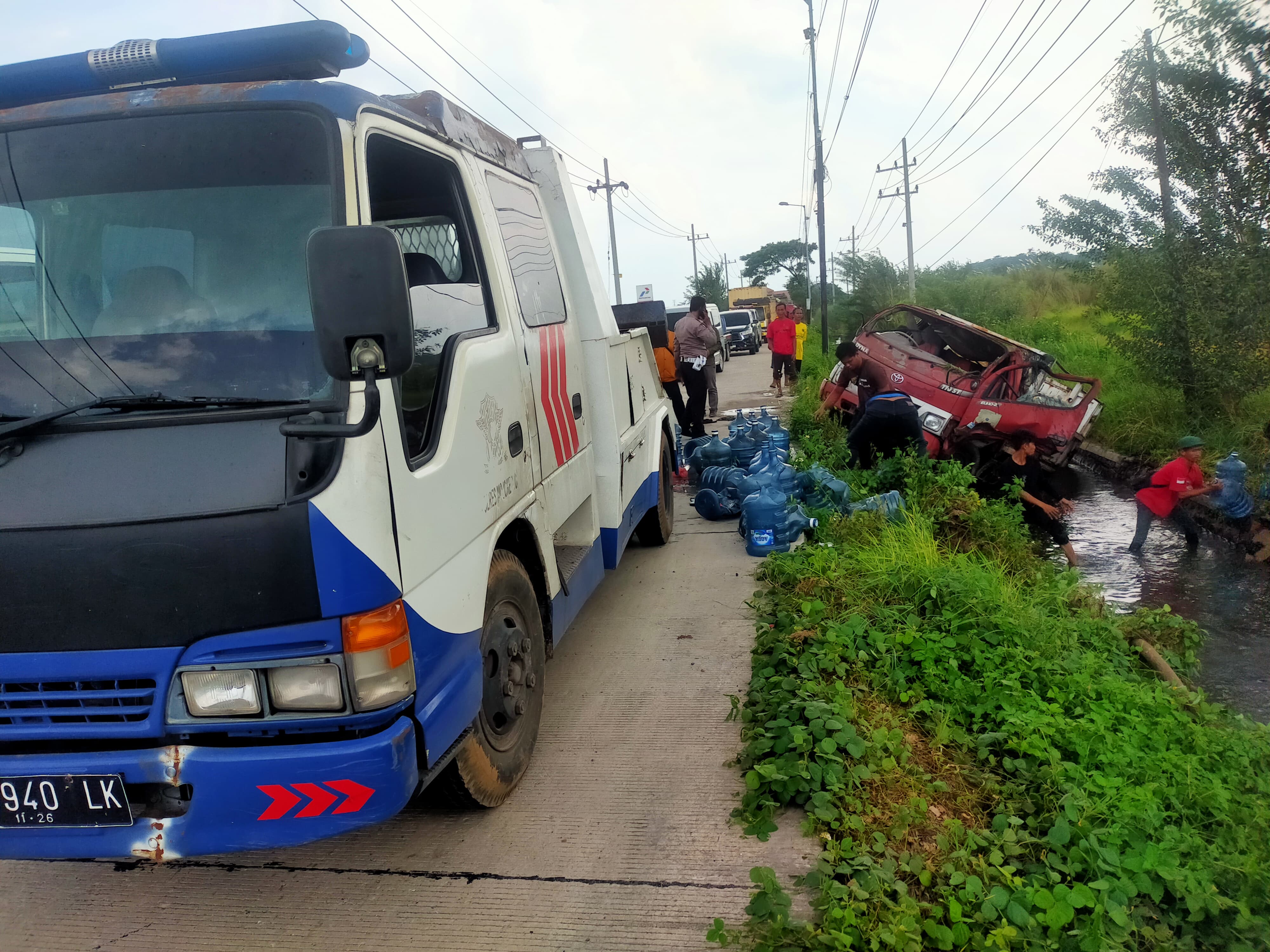 DIDEREK: Truk muatan air mineral galon merek Aqua nyungsep di parit Desa Ngarjo, Kecamatan Mojoanyar, Selasa (4/2) siang.