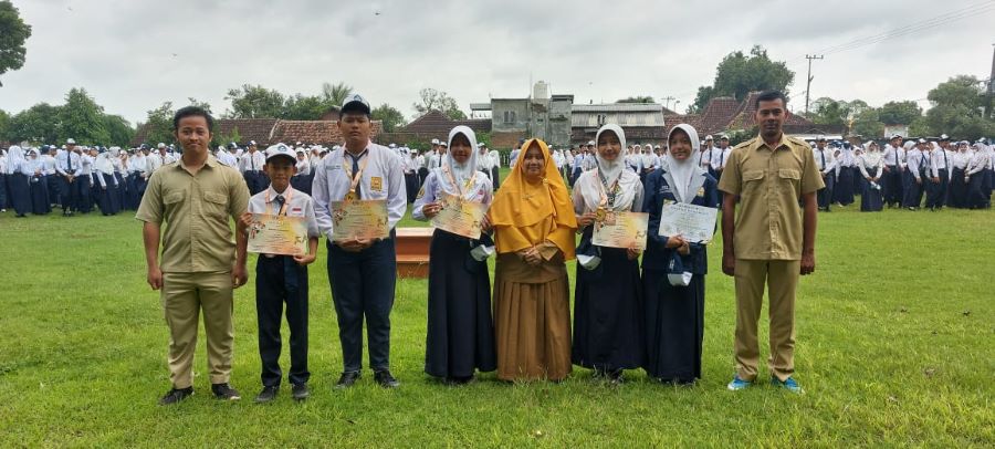 TOTALITAS: Kepala SMPN 1 Dlanggu Andry Isweliyah menyerahkan piagam apresiasi kejuaraan pencak silat kepada siswa berprestasi.