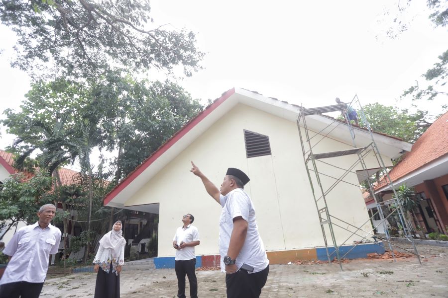 TERDAMPAK: Kepala SMPN 3 Mojokerto Rejo saat meninjau perbaikan atap pada bangunan sekolah yang mengalami kerusakan usai diterjang angin kencang.
