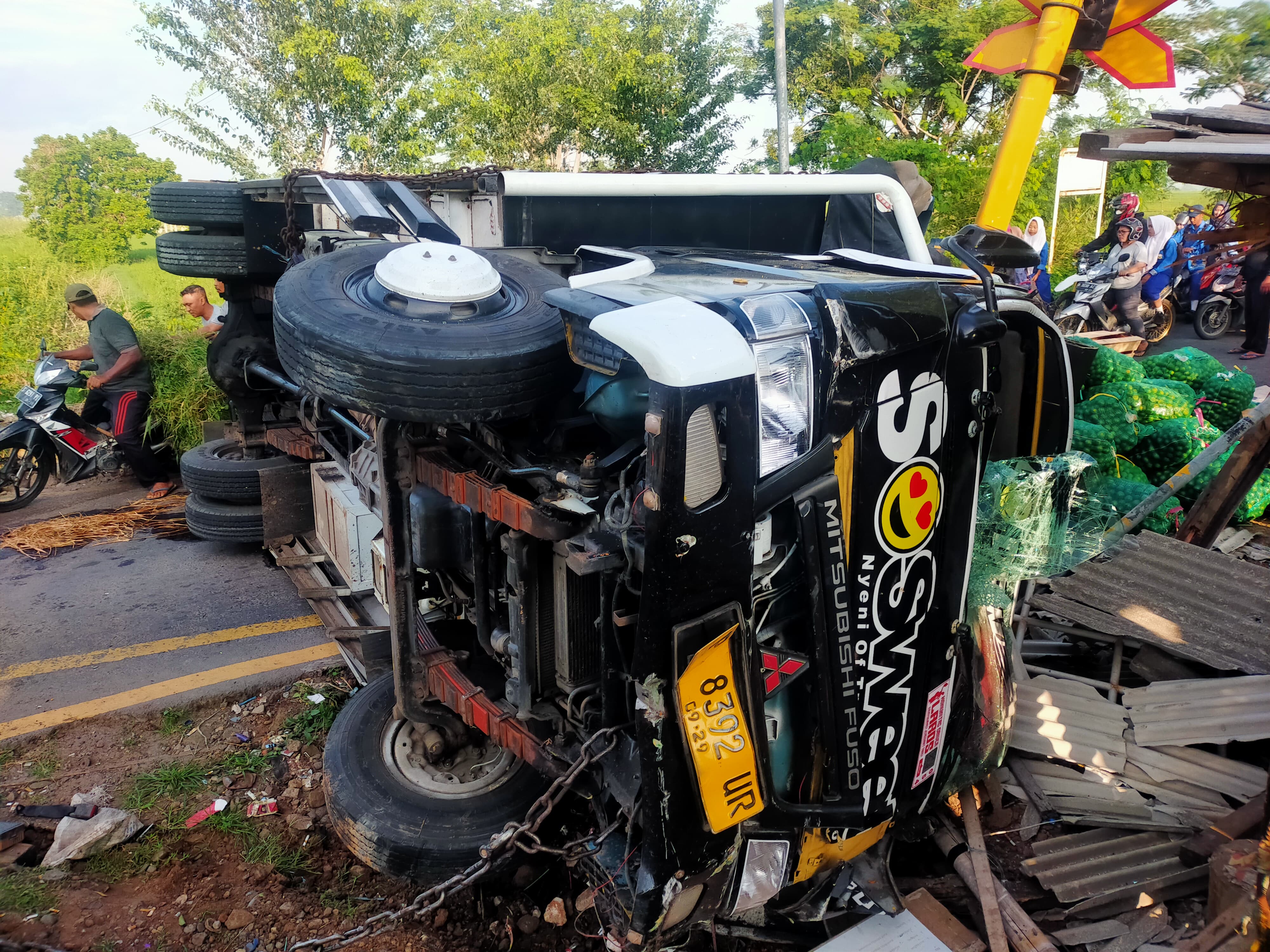 TERGULING: Truk muatan buah terguling perlintasan Damarsi, Desa Kepuhanyar, Kecamatan Mojoanyar, Kamis (13/2).