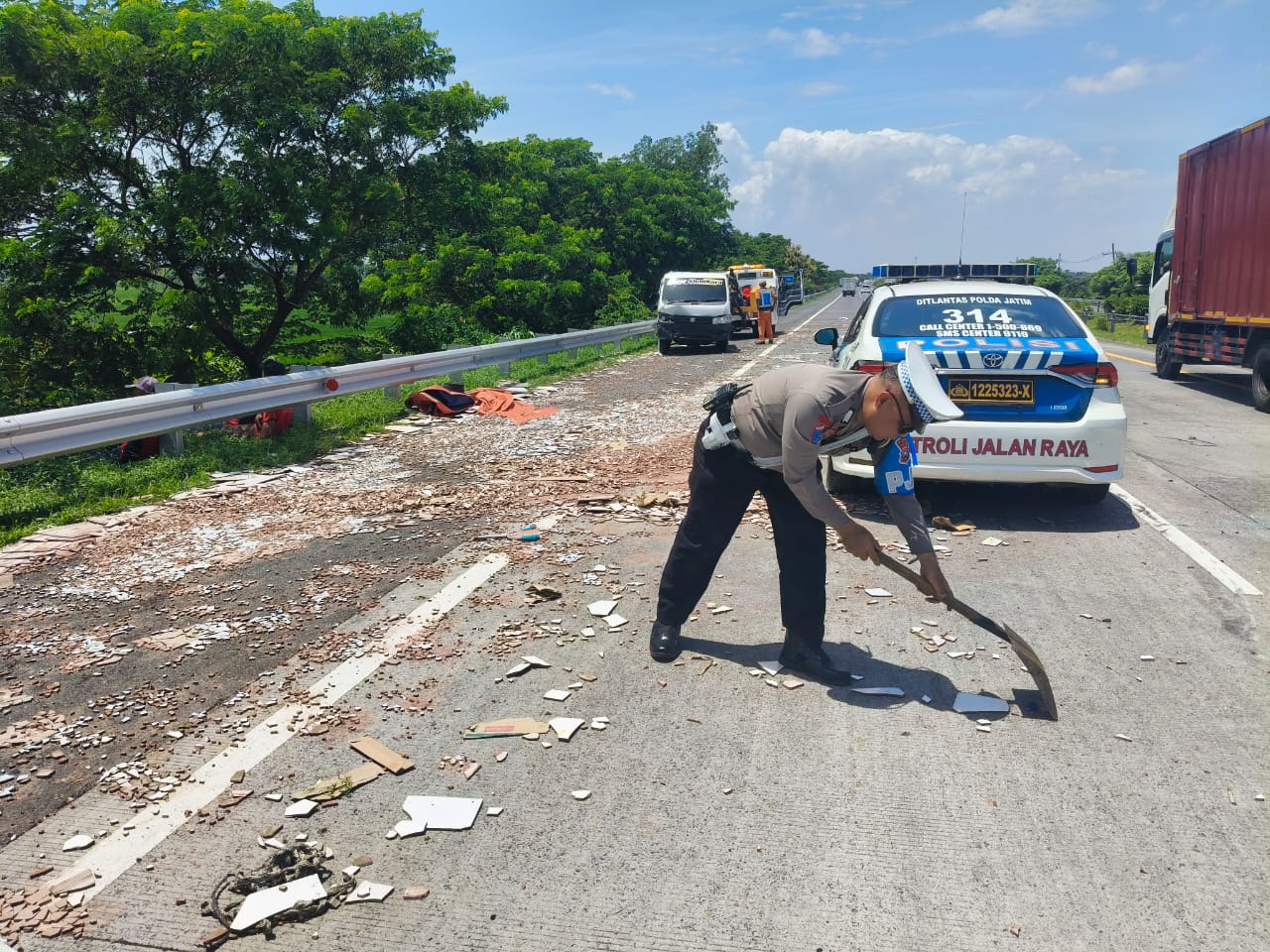 TERCECER: Petugas Unit 3 PJR Ditlantas Polda Jatim membersihkan puing keramik muatan pikap yang kecelakaan di KM 715 Tol Sumo, Desa Mojolebak, Kecamatan Jetis, Kabupaten Mojokerto, Kamis (13/2).