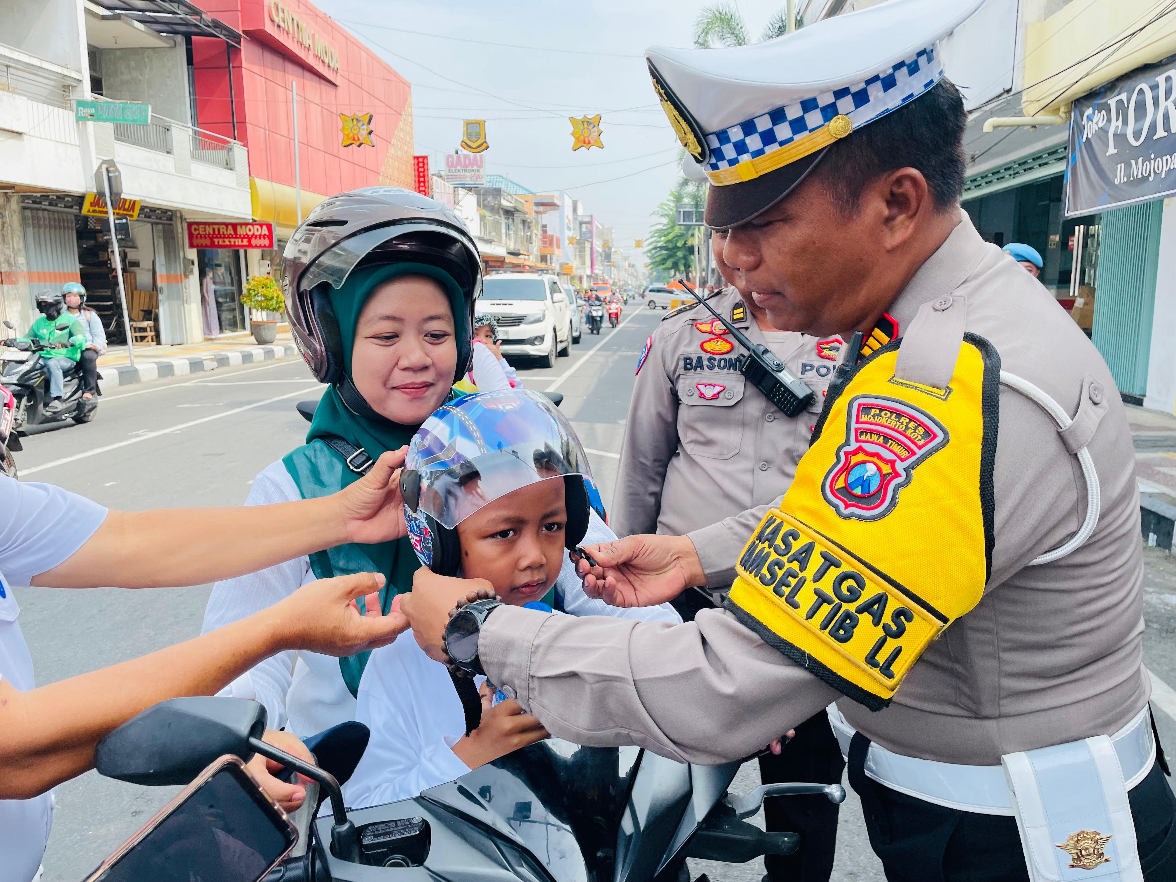 SARANA EDUKASI: Kasat Lantas Polres Mojokerto Kota AKP Mulyani memberi helm gratis kepada pengendara di Jalan Mojopahit, Selasa (18/2).