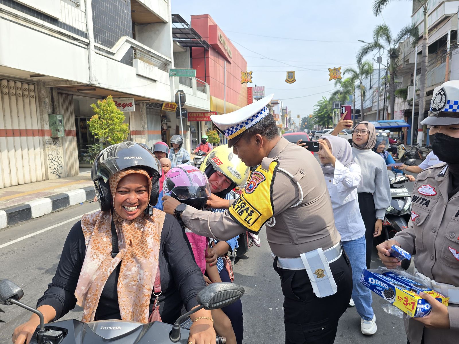 SARANA EDUKASI: Kasat Lantas Polres Mojokerto Kota AKP Mulyani memberi helm gratis kepada pengendara di Jalan Mojopahit, Selasa (18/2).