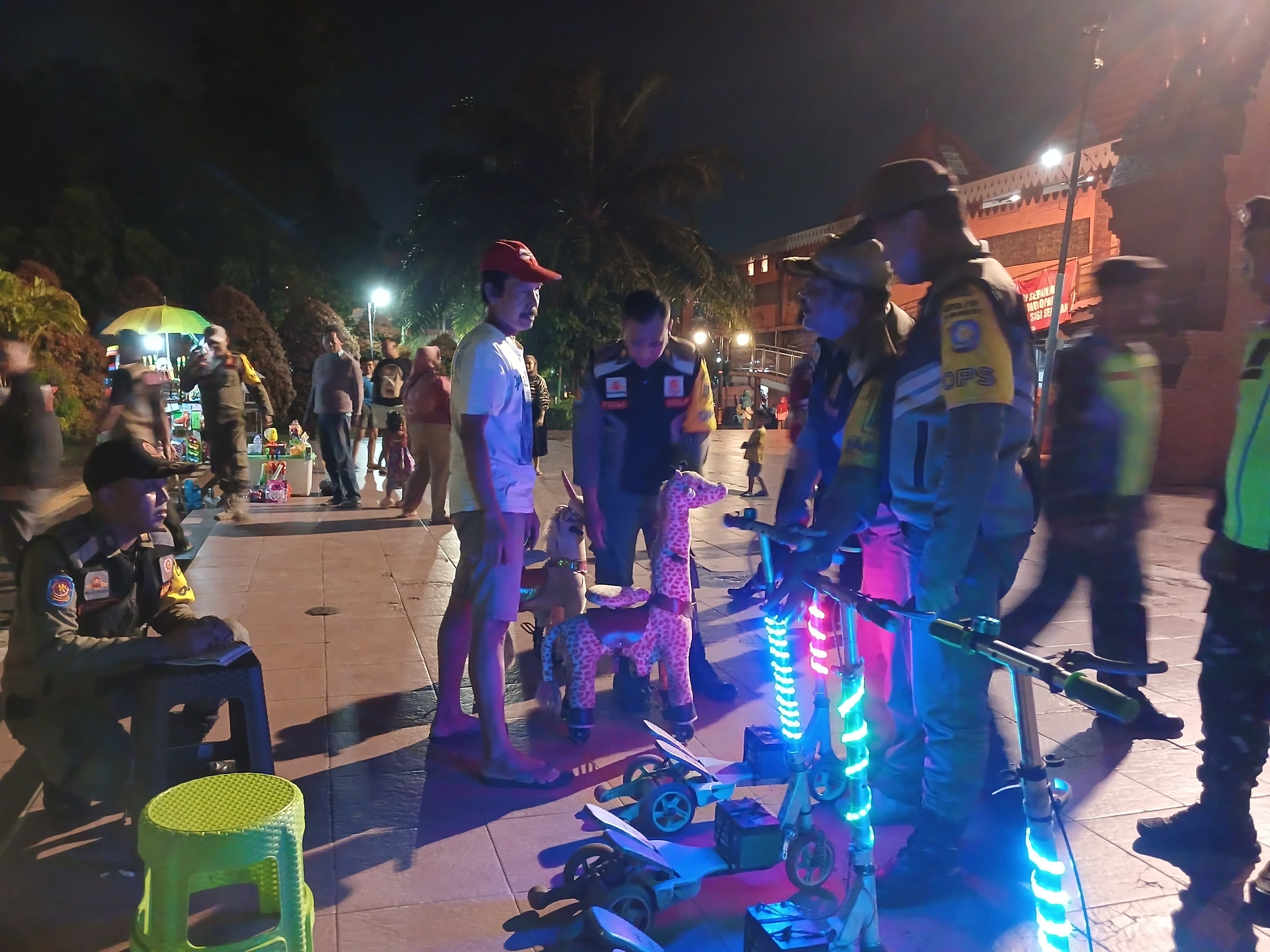 DITERTIBKAN: Petugas Satpol PP Kota Mojokerto mengangkut skuter dan motor mainan yang disewakan di Alun-Alun Wiraraja, Sabtu (22/2) malam.