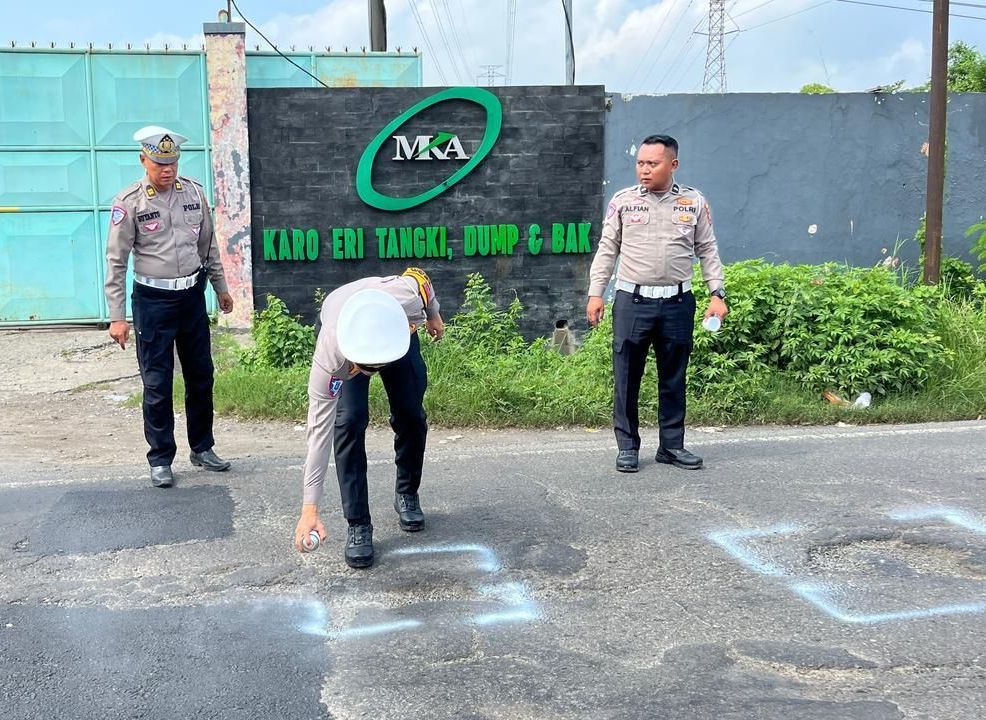 ANTISIPASI: Petugas Satlantas Polres Mojokerto bersama Dishub menandai lubang jalan nasional di Simpang Lima Kenanten.