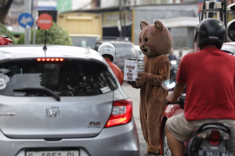 PENGEMIS DADAKAN: Seorang pengemis memakai kostum boneka panda leluasa beroperasi di perempatan Sooko Jalan RA Basuni, kemarin.