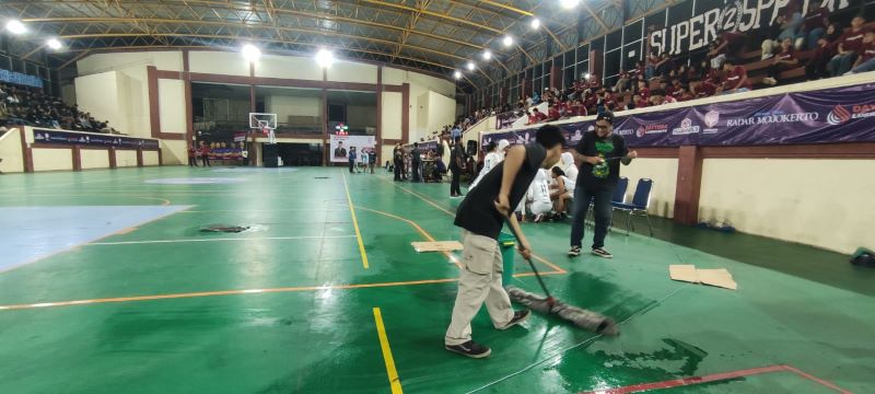 TERGANGGU: Petugas pertandingan Ramadan League mengepal lantai yang basah akibat bocornya atap di GOR dan Seni Mojopahit yang mengakibatkan pertandingan basket tertunda, Sabtu (15/3) malam.