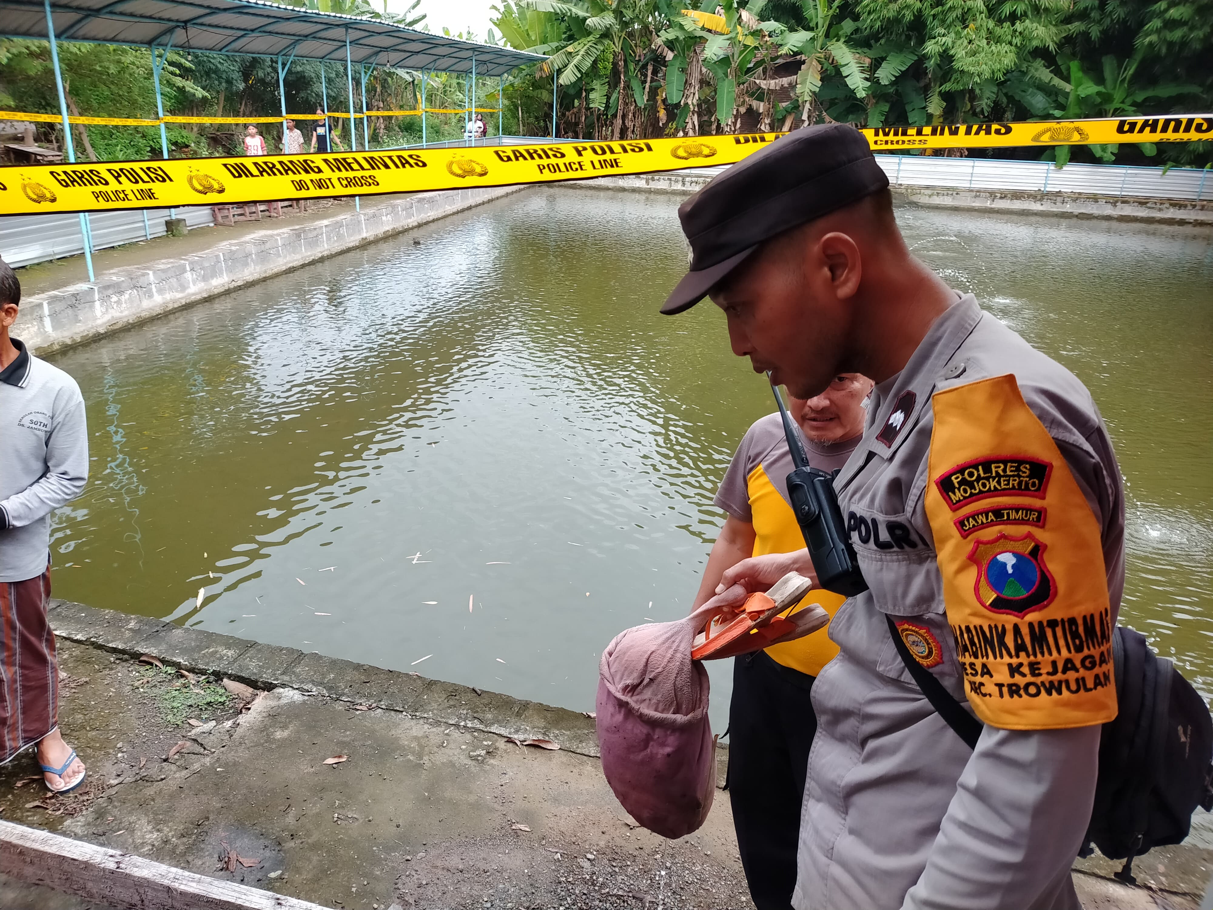 SAKSI BISU: Petugas mengamankan sandal dan boneka milik korban dari lokasi untuk dijadikan barang bukti.