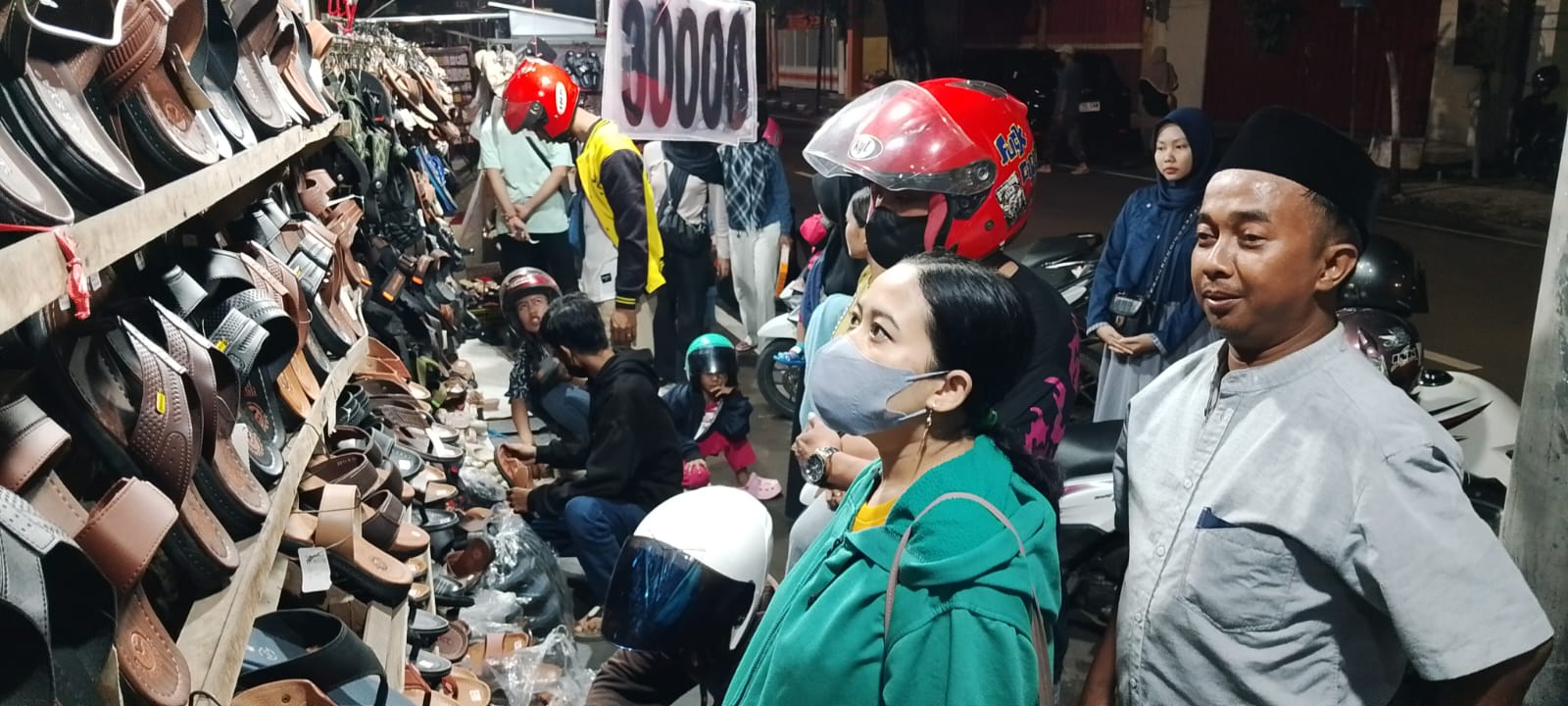 BERKAH LEBARAN: Nuril, pedagang sandal di Jalan PB Sudirman Kota Mojokerto melayani pembeli, Sabtu (30/3) malam.