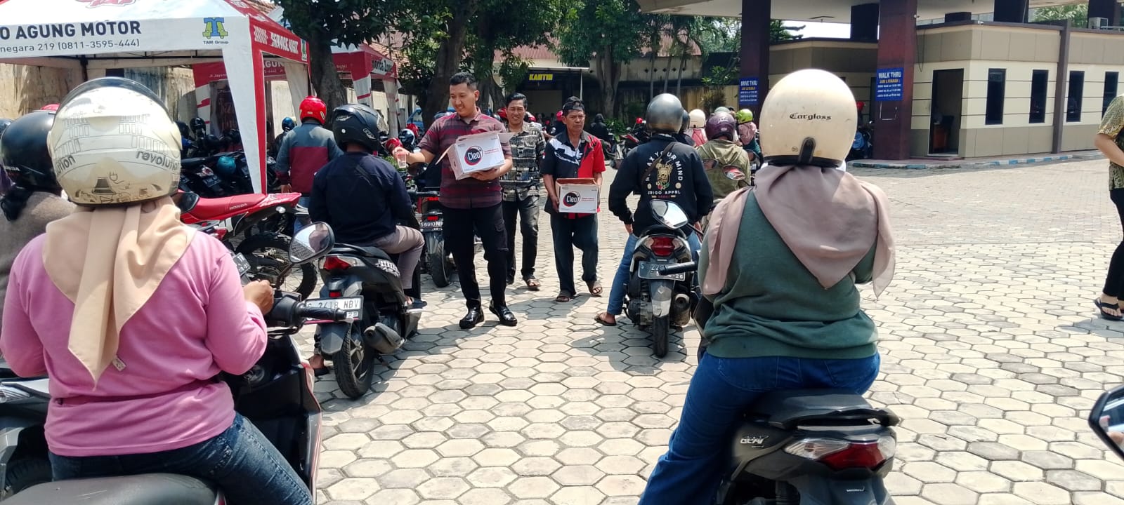 AIR GRATIS: Petugas kantor KB Samsat Kabupaten Mojokerto membagikan air minum gratis kepada antrean wajib pajak.