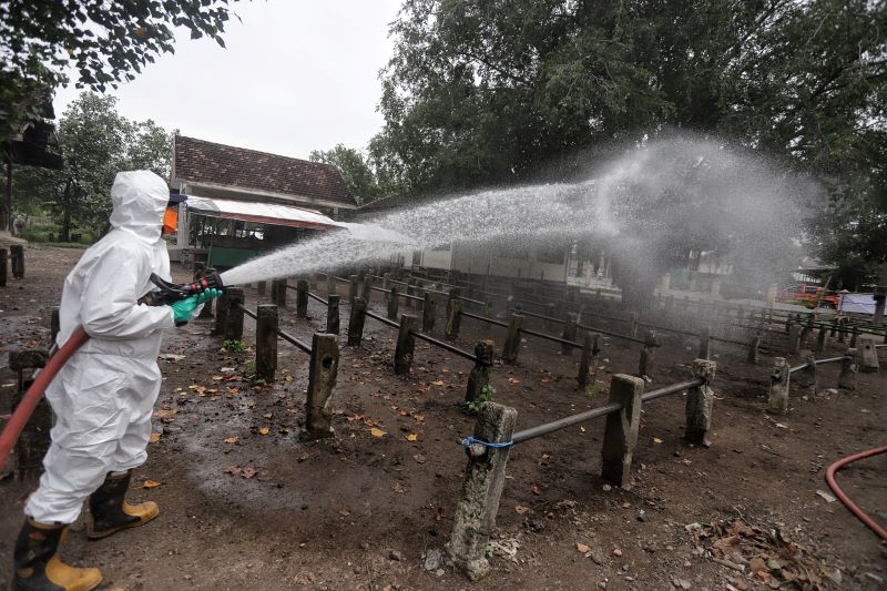 TERTANGANI: Petugas melakukan sterilisasi pasar hewan di Desa Ngrame, Kecamatan Pungging, menggununakan cairan disinfektan untuk mencegah penyebaran PMK, Januari tahun lalu