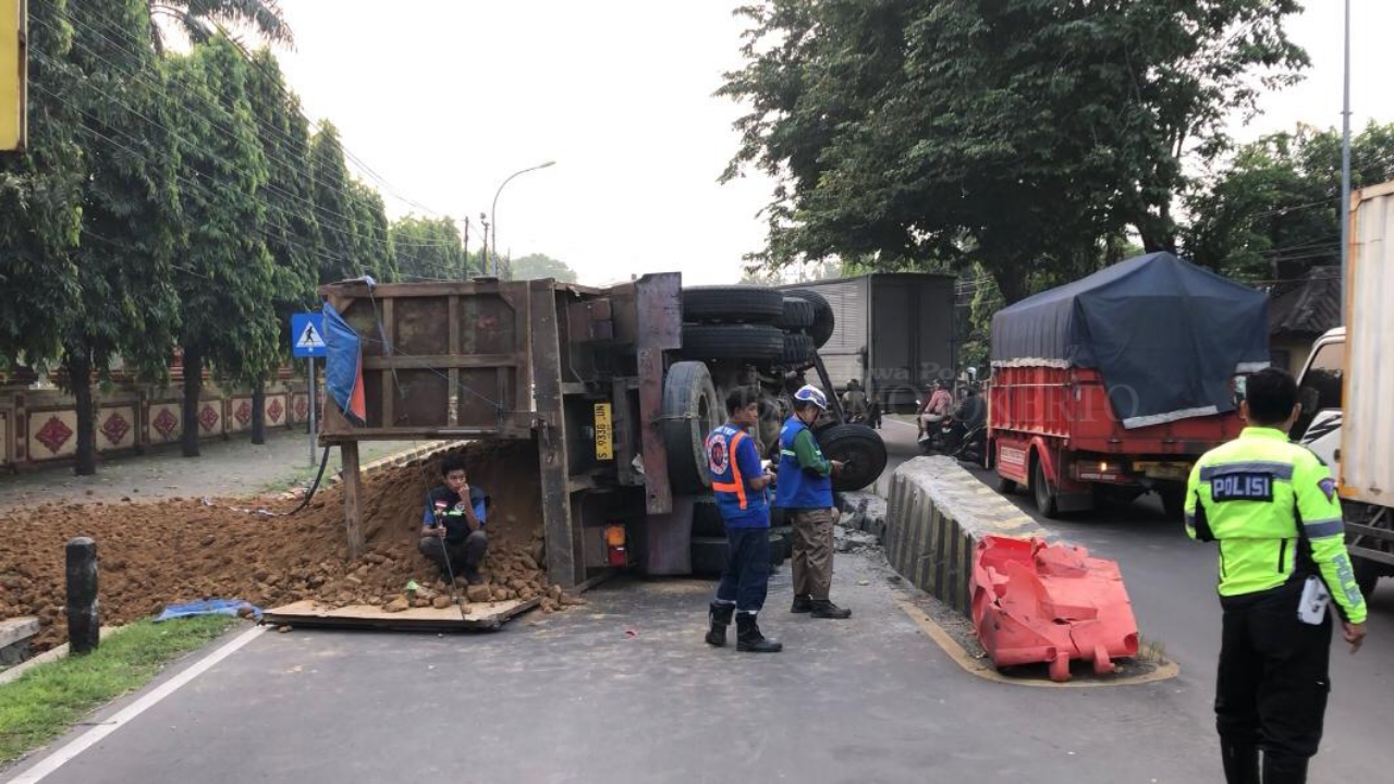CELAKA: Kondisi truk yang terguling usai menabrak separator depan SPN Mojokerto, Jumat (25/4).