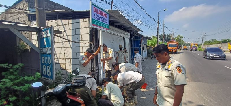 PERINGATAN: Petugas Satpol PP Kabupaten Mojokerto bersama forkopimca dan perangkat desa memasang plang di depan warung remang-remang, Jalan Raya Desa Japanan, Kecamatan Kemlagi, Rabu (7/5).