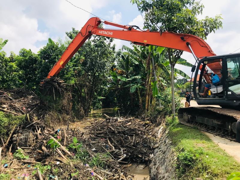 MENUMPUK: Pekerja DPUPR Kabupaten Mojokerto mengeruk sampah bambu di aliran Sungai Marmoyo, Desa Mojowiryo, Kecamatan Kemlagi.