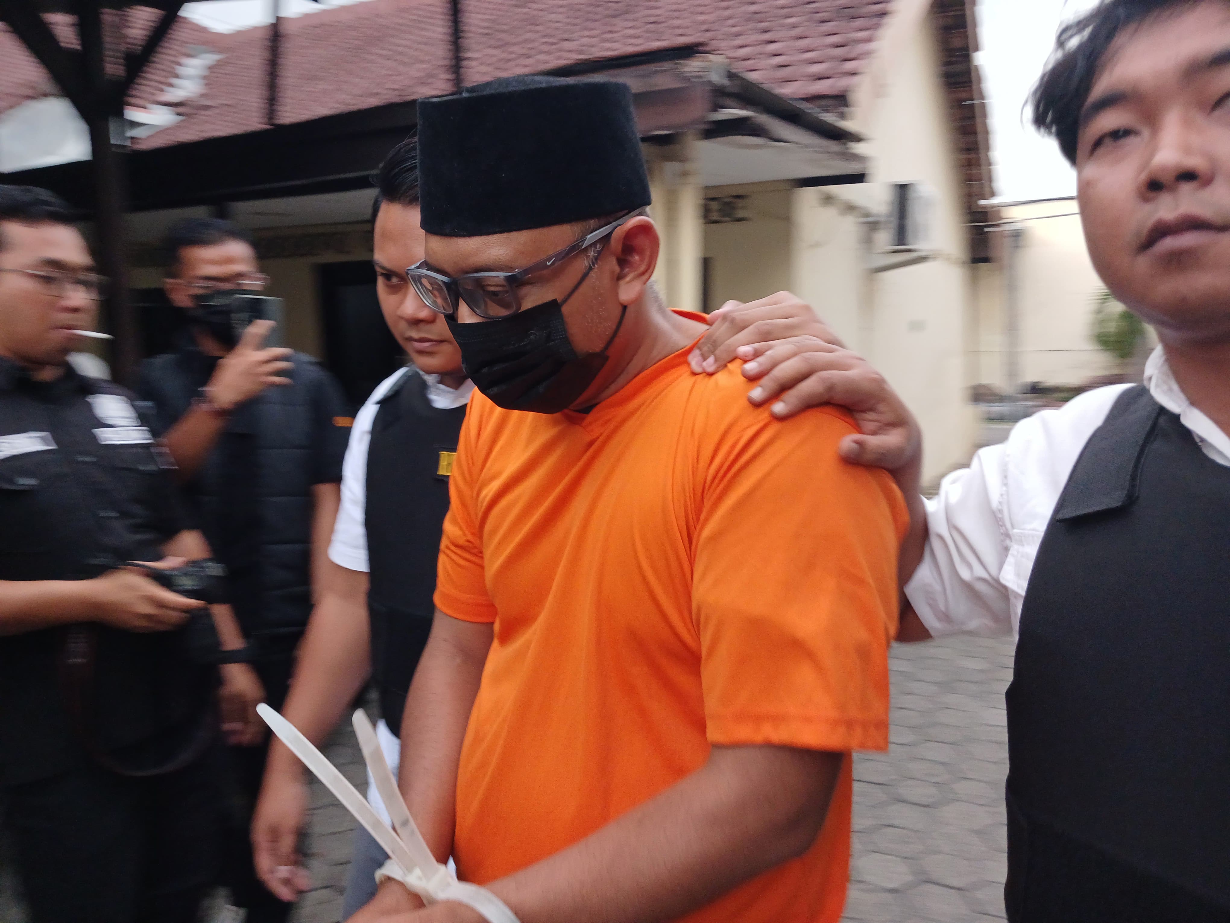 DITAHAN: Tersangka Bagus Lukita Adhi dikeler petugas di Mapolres Mojokerto Kota, Rabu (14/5).