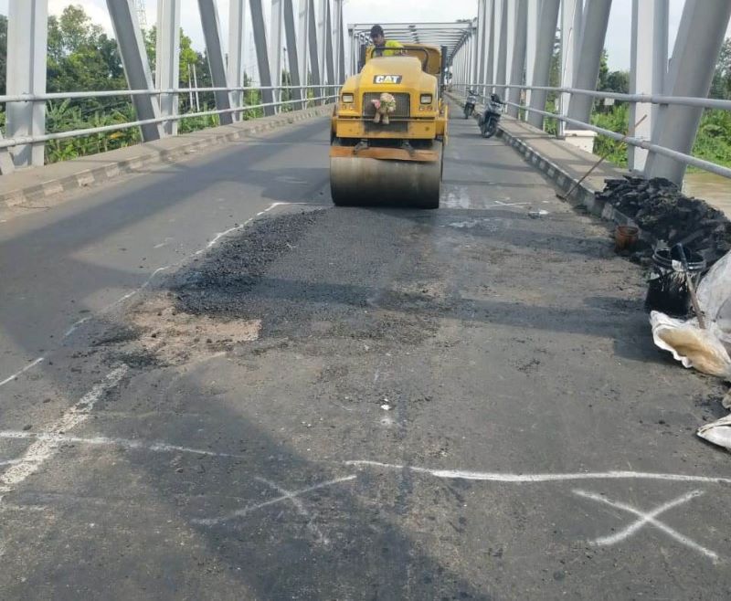 TAMBAL SULAM: Pekerja Dinas PUPR Perakim Kota Mojokerto memperbaiki jalan di Jembatan Gajah Mada yang mengalami kerusakan, kemarin (16/5).
