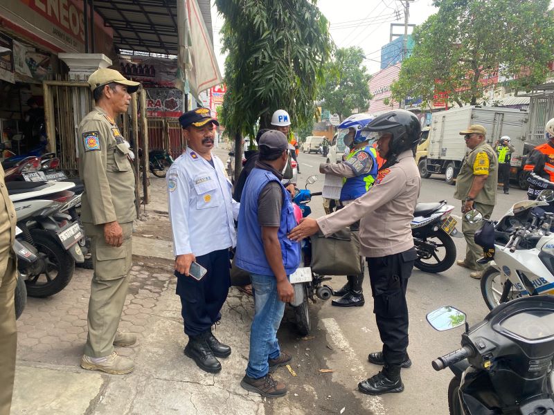 MERESAHKAN: Petugas membawa jukir liar yang beroperasi di sekitar Pasar Tanjung Anyar, Kota Mojokerto, ke mapolres, kemarin (20/5).