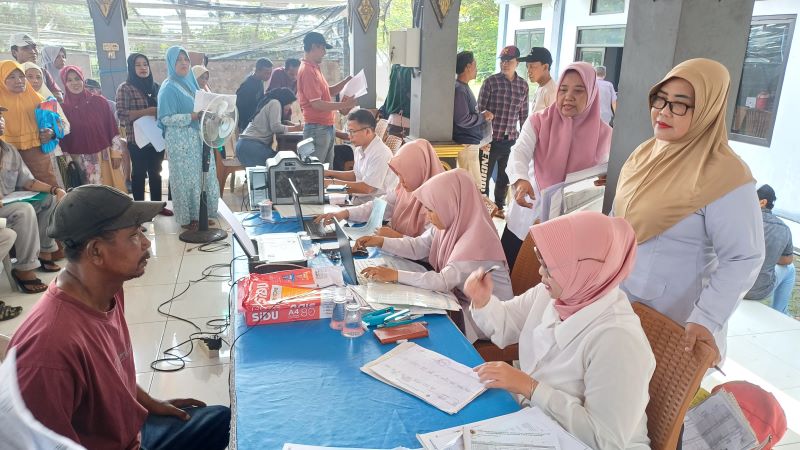 LAYANAN: Hj Siti Maidah SH sedang mengecek dan mendampingi petugas Dispendukcapil dalam proses input data saat pengurusan adminduk di balai desa Ngrowo Kecamatan Bangsal.&nbsp;