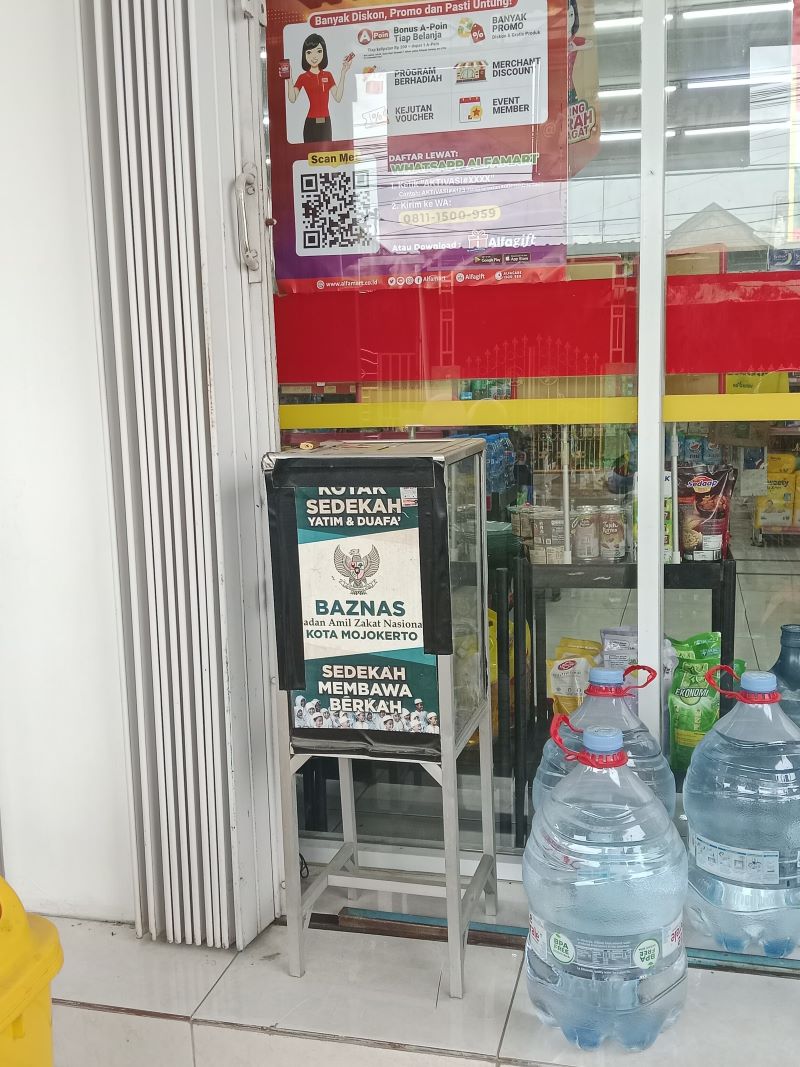 DEKAT TONG SAMPAH: Sebuah kotak amal bertuliskan Baznas Kota Mojokerto ditempatkan berdekatan tong sampah di teras minimarket kawasan Kelurahan Meri, Kecamatan Kranggan, Kota Mojokerto, kemarin