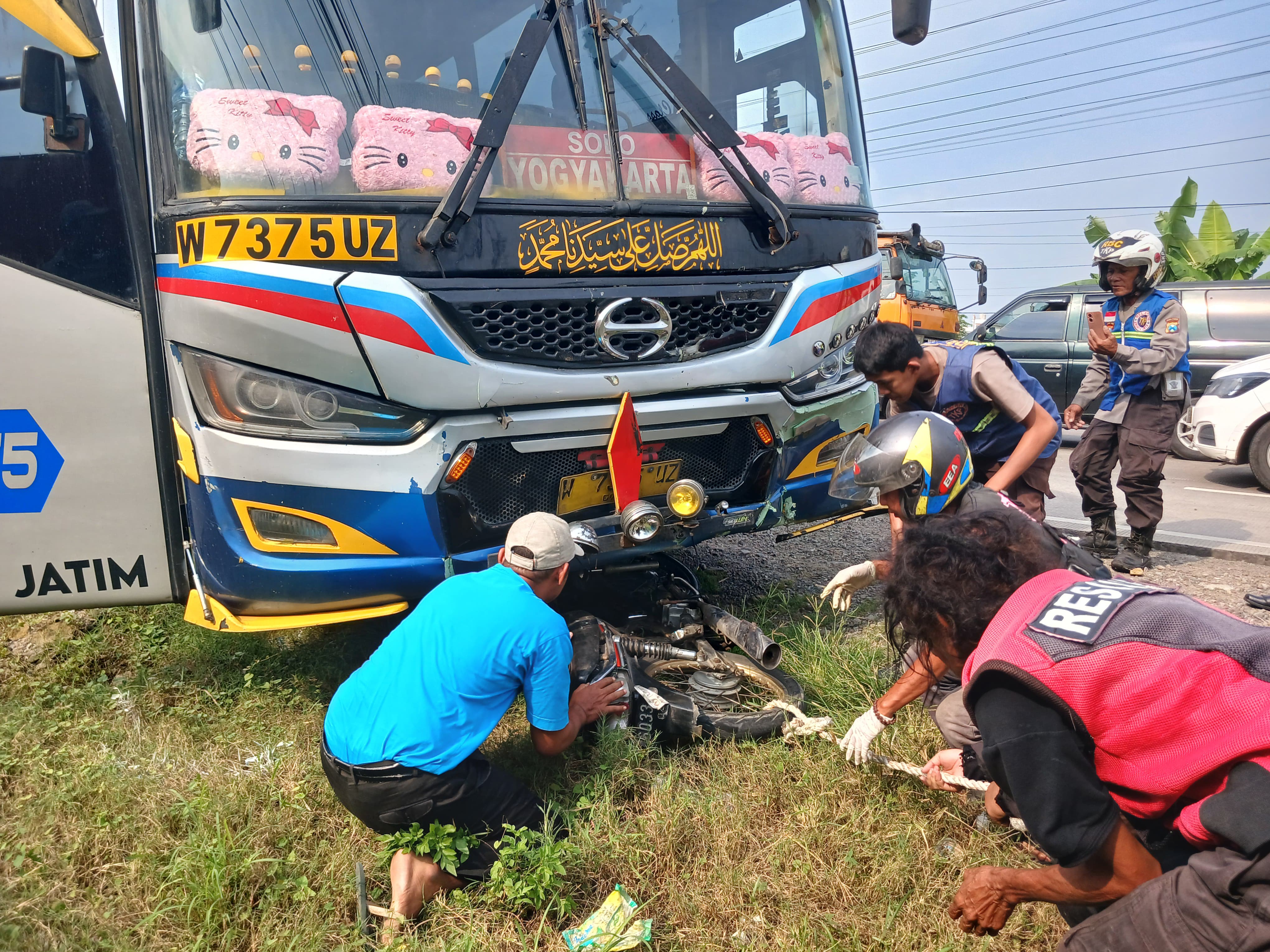 TERSANGKUT: Petugas mengevakuasi motor korban yang terseret di kolong bus dalam kecelakaan di Jalan Raya Bypass Mojokerto, Senin (2/6).