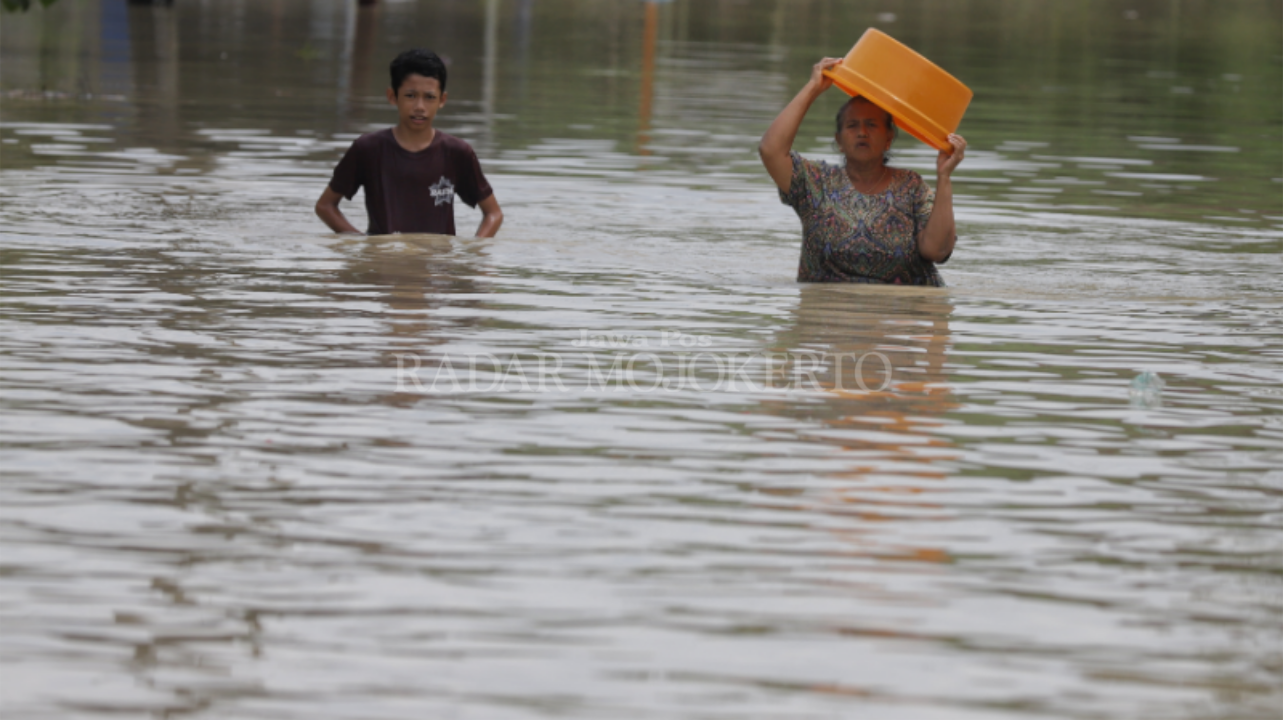 BENCANA RUTIN: Warga Dusun Klanting, Desa Pulorejo, Kecamatan Dawarblandong melintasi banjir yang merendam kampungnya.
