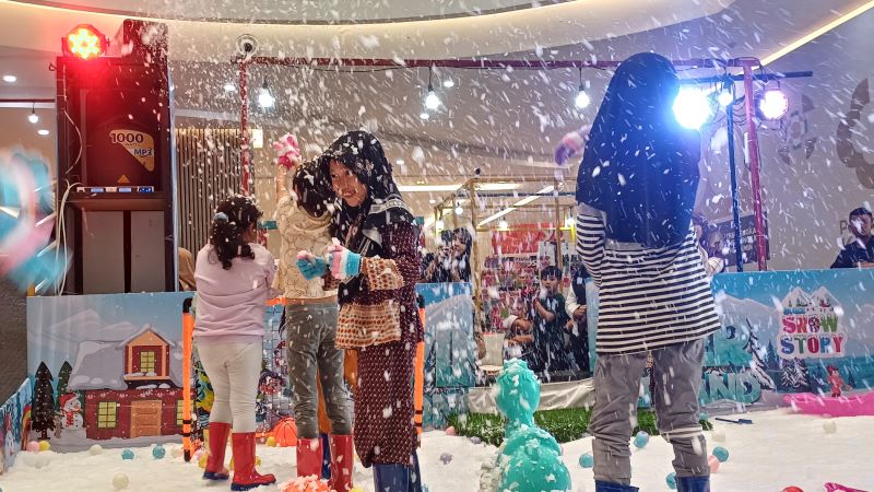 HUJAN: Anak-anak sangat senang menikmati hujan salju di arena bermain.