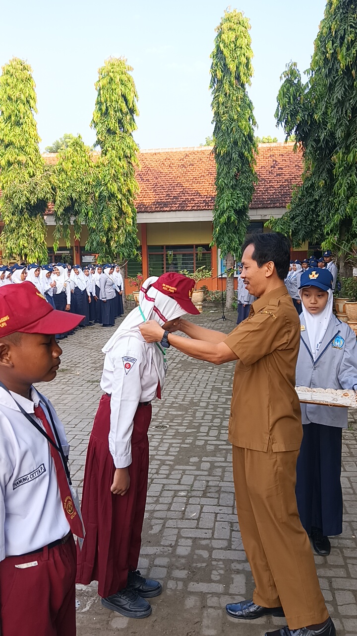 SEMANGAT BARU: Kepala SMPN 1 Puri Nanang Wahyuningaji menyematkan tanda pengenal peserta MPLS, kemarin.
