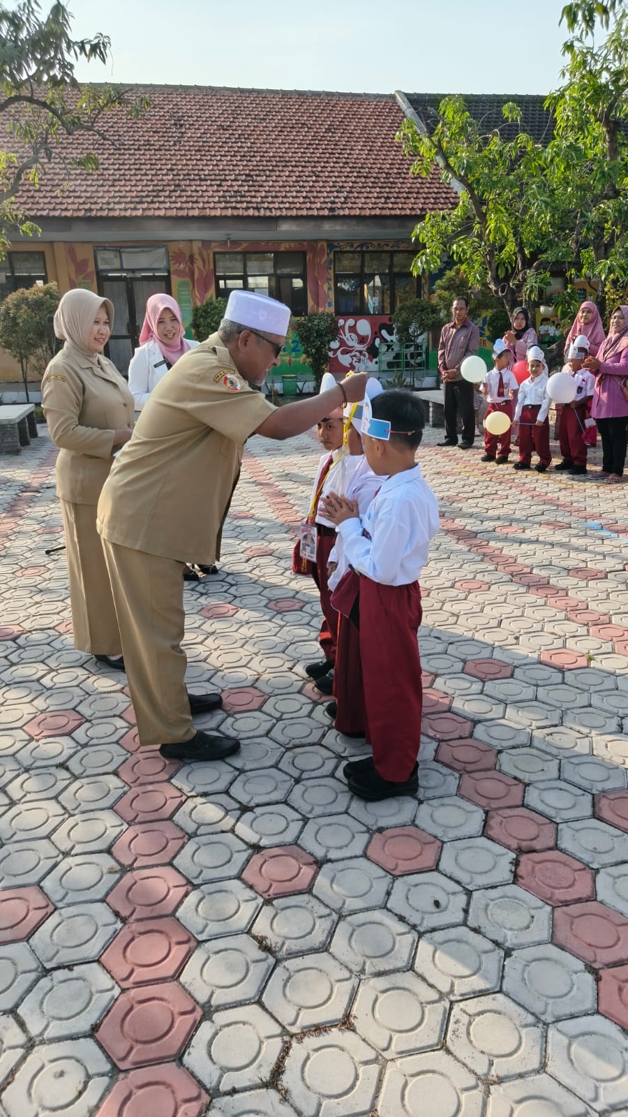 RIANG GEMBIRA: Kepala SDN Jabon 2 Nurul Cholidi menyematkan simbol MPLS kepada peserta didik baru saat upacara pembukaan, Senin (14/7).