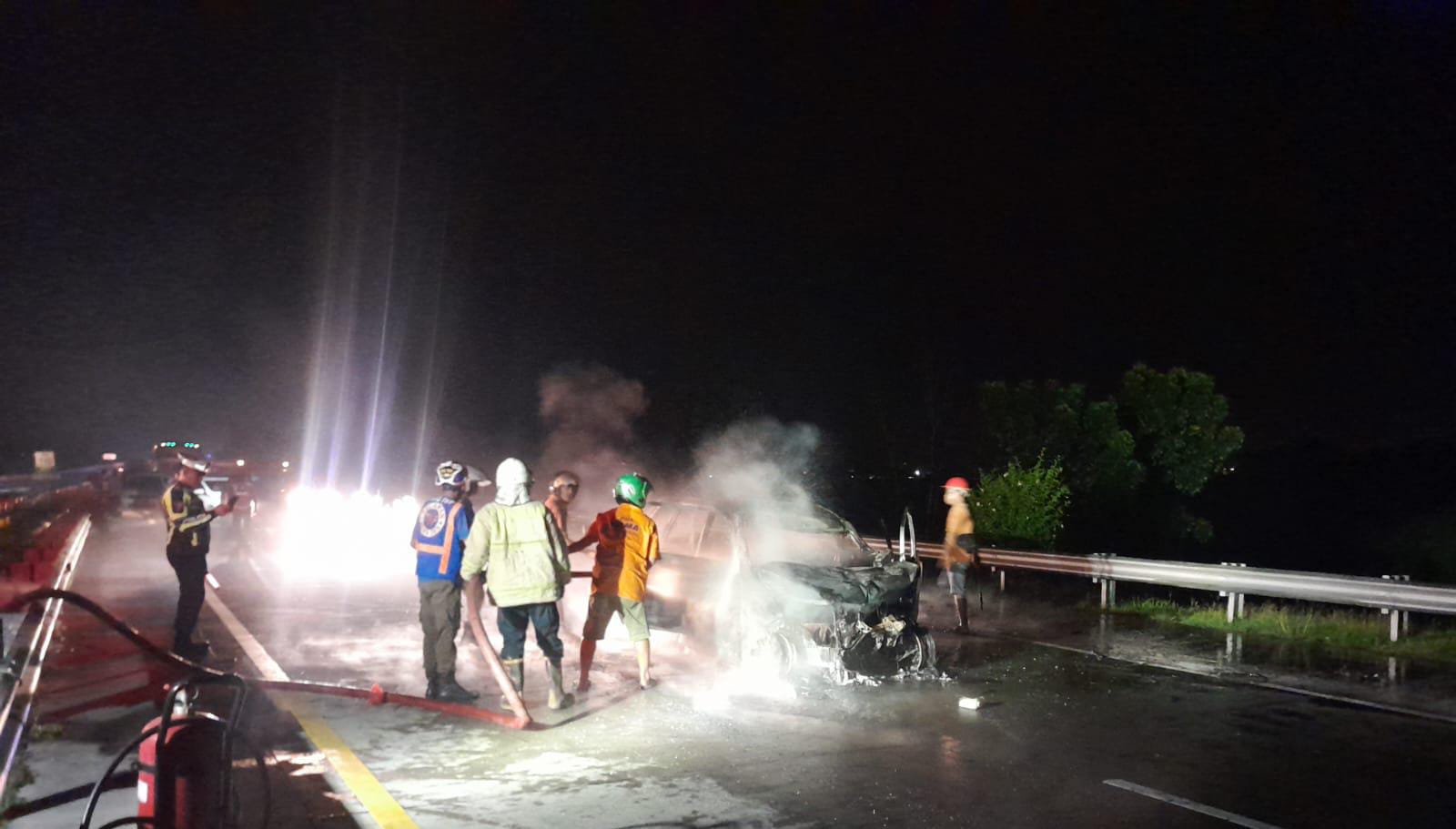 Petugas pemadam kebakaran sedang memadamkan api yang berkobar di seluruh bodi kendaraan di ruas tol Jombang-Mojokerto.
