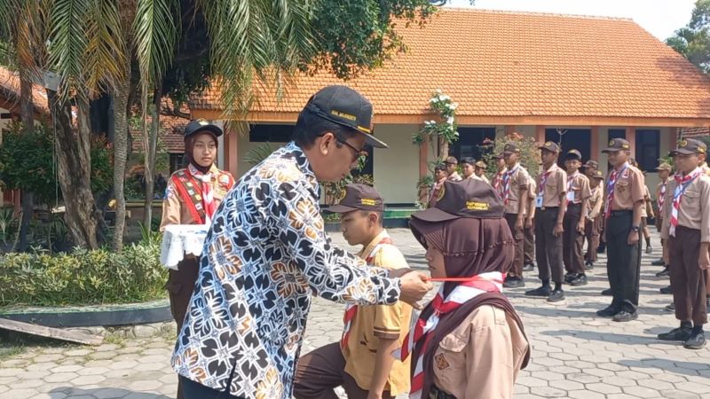 SAMBUT SISWA: Kepala SMPN 1 Kutorejo Supriyadi menyematkan tanda peserta MPLS kepada siswa baru, Senin (14/7).