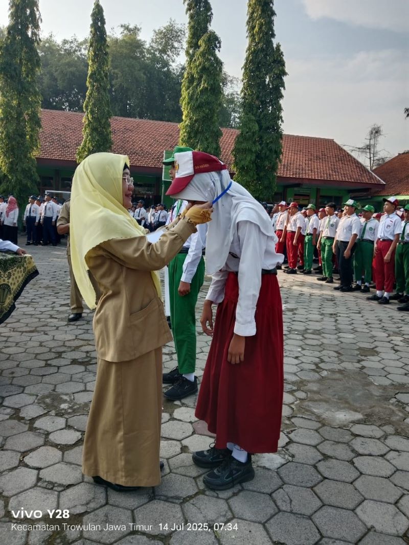 RAMAH: Kepala SMPN 1 Trowulan Ridha Dwi Wulansari, M.Pd, membuka MPLS bertemakan ramah dengan penyematan kartu peserta MPLS.