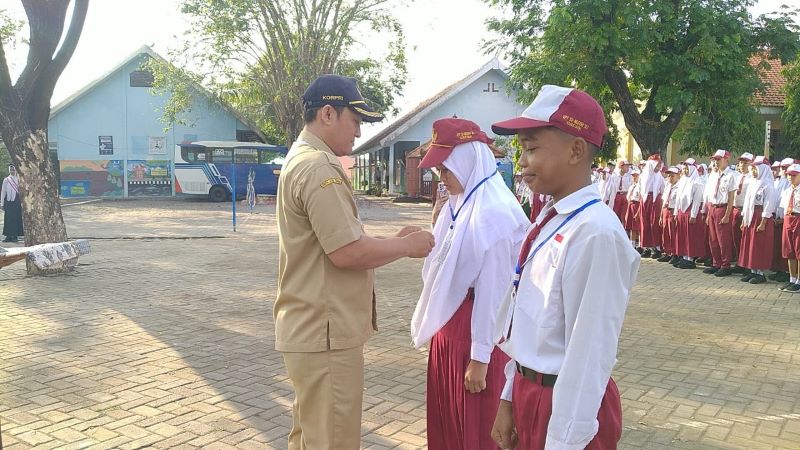 PENUH SEMANGAT: Kepala SMPN 2 Dawarblandong Suntoro menyematkan kartu peserta MPLS kepada peserta saat upacara pembukaan MPLS ramah.