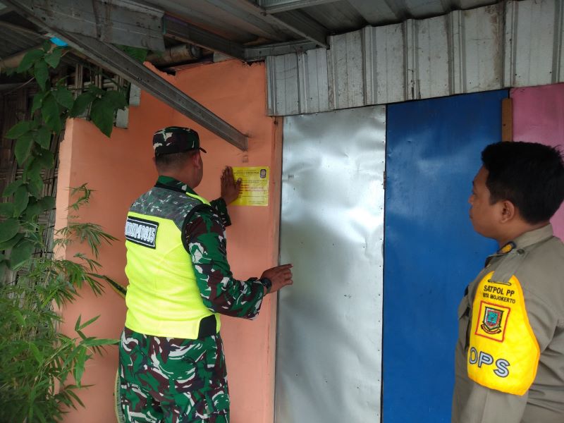 DIPERINGATKAN: Petugas Satpol PP Kota Mojokerto memasang stiker larangan kegiatan prostitusi di warung remang-remang sekitar perlintasan KA Gunung Gedangan, Selasa (29/7).