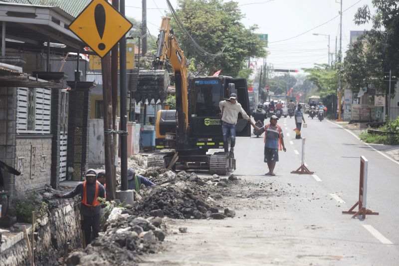 DIKEBUT: Pekerja tengah menggarap pemasangan U-ditch pada proyek pembangunan buang air kotor sistem drainase perkotaan di Jalan Raya Desa Kupang, Kecamatan Jetis, kemarin (8/8).