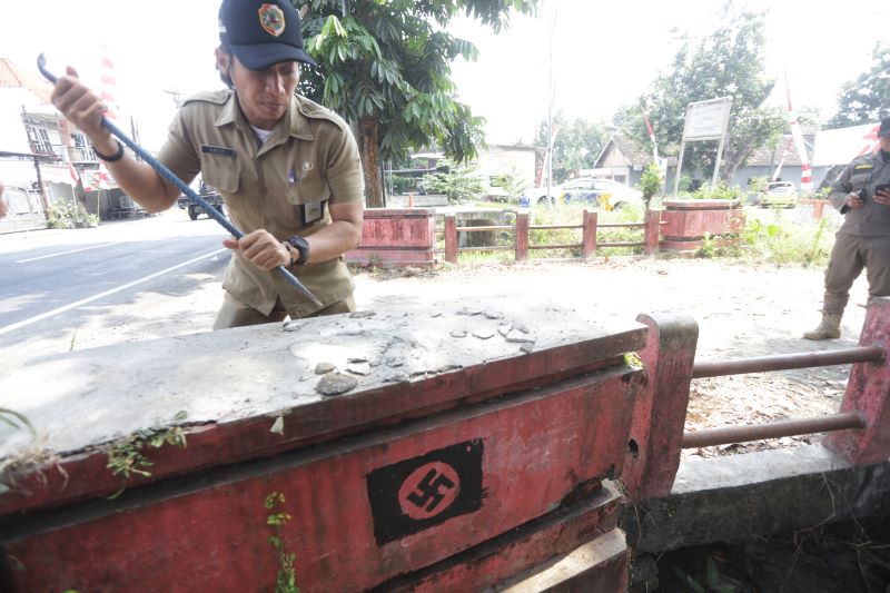 MENGEJUTKAN: Pegawai Kecamatan Gedeg dan Satpol PP Kabupaten Mojokerto membongkar simbol fasisme berlogo Nazi yang menempel di gapura pagar Sekolah Rakyat di Jalan Raya Desa Kemantren, Kecamatan Gedeg