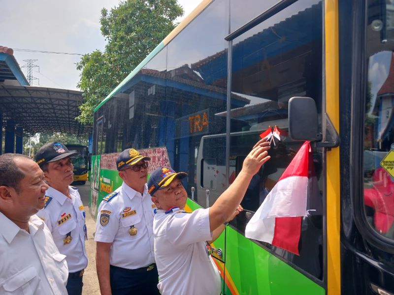 SEMARAK KEMERDEKAAN: Kepala Dishub Jatim Nyono memasang bendera merah putih ke badan bus di Terminal Kertajaya, Kota Mojokerto, kemarin (14/8).