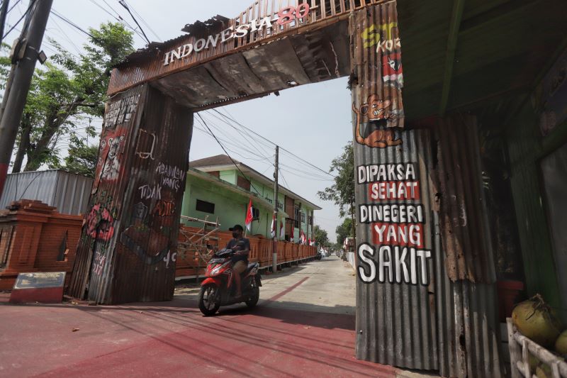 DEKORASI GAPURA: Warga melintasi gapura di Gang Puskesmas, Desa Kedungmaling, Kecamatan Sooko, Kabupaten Mojokerto yang dibangun sebagai dekorasi menyambut Agustusan, Rabu (13/8).