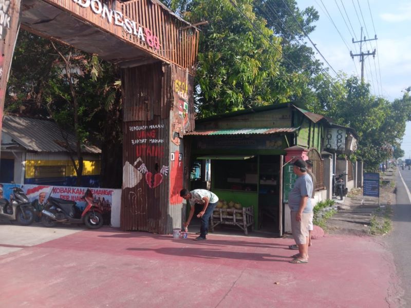 MENDADAK DIHAPUS: Sejumlah warga berinisiatif menghapus mural dan grafiti pada gapura dari seng bekas yang digunakan sebagai dekorasi 17 Agustusan, Rabu (13/8).