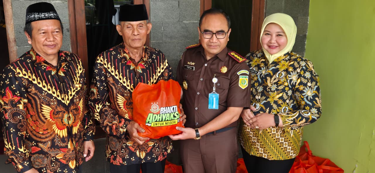 TEBAR KEBAIKAN: Kajari Kabupaten Mojokerto Endang Tirtana dan Ketua IAD Kabupaten Mojokerto Ny. Yasinta Tirtana menyerahkan paket sembako kepada Purnaja menyambut Harla Kejaksaan RI Ke-80 Tahun 2025.