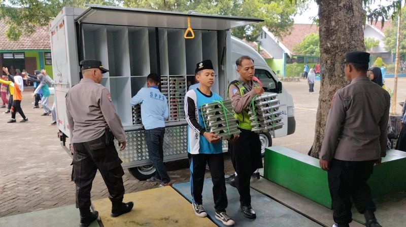 BERTAMBAH: Paket makanan bergizi dari SPPG Ponpes Segoro Agung dikawal petugas Polsek dan Koramil Trowulan saat uji coba penyaluran MBG ke siswa sekolah, Agustus lalu.