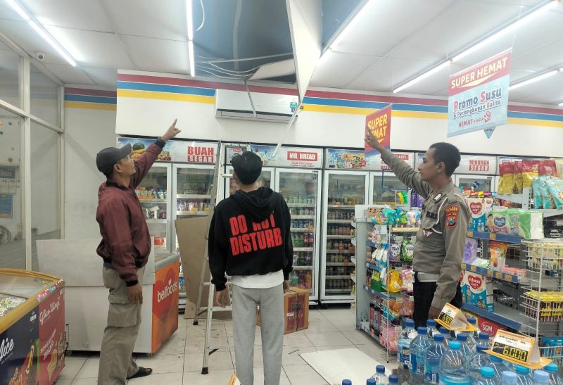 DIJEBOL: Petugas Polsek Ngoro menunjukkan atap minimarket di Dusun Kecapangan, Desa/Kecamatan Ngoro, yang dijebol maling, Selasa (23/9) dini hari.
