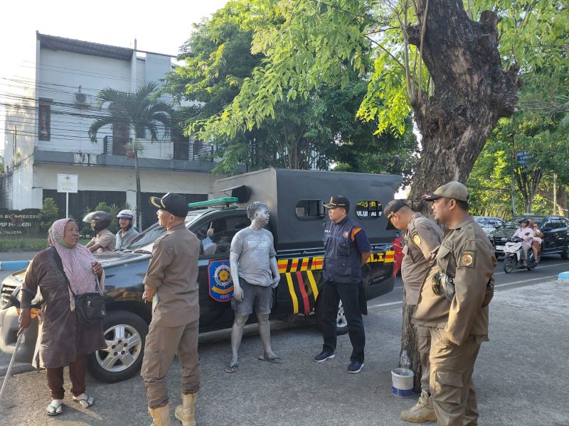 MEMBANDEL: Petugas menjaring pengemis dan manusia silver di simpang empat Awang-Awang, Kecamatan Mojosari, Minggu (28/9).