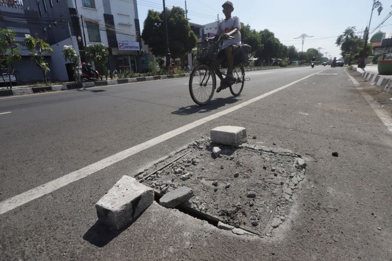 BAHAYA: Warga melintas di area tutup got yang amblas di Jalan Empunala, Kota Mojokerto, kemarin (5/10).