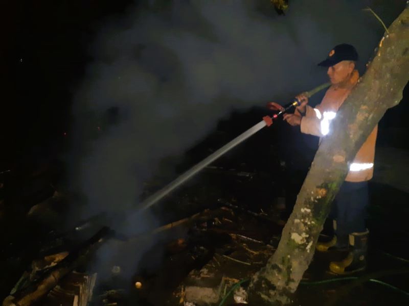 DIJINAKKAN: Petugas damkar melakukan pembasahan pada kandang sapi di Dusun Genengan, Desa Randugenengan, Kecamatan Dlanggu, yang ludes terbakar Sabtu (4/10) malam.