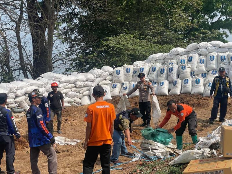 DITAMBAL: Relawan bersama kepolisian menambal dinding sekam jalur penyelamat tikungan Gotekan, Desa/Kecamatan Pacet, Kamis (9/10).