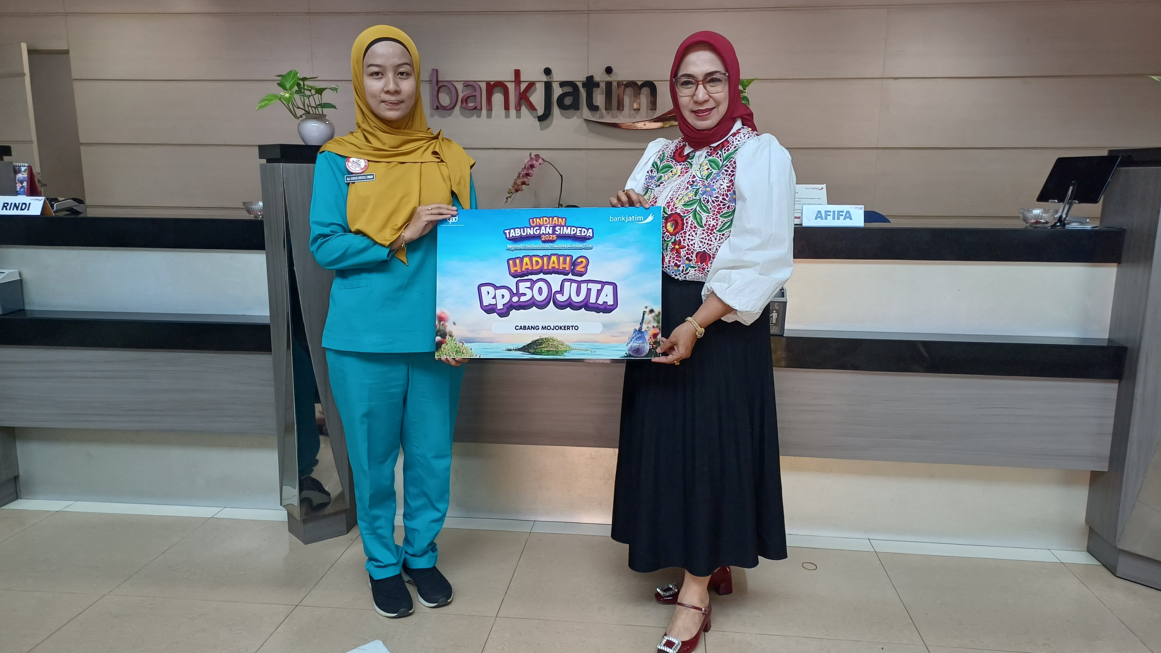 SENANG: Pemimpin Bank Jatim Cabang Mojokerto, Sugiastuti secara simbolis menyerahkan hadiah undian Simpeda Rp 50 Juta ke Lukluk Afifatul Umroh di kantor Bank Jatim Cabang Mojokerto.