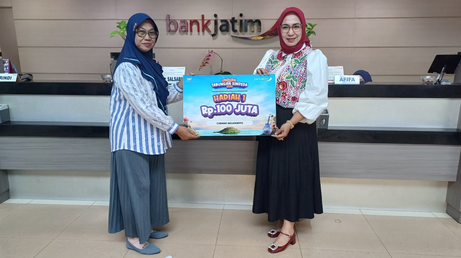 SENANG: Pemimpin Bank Jatim Cabang Mojokerto, Sugiastuti secara simbolis menyerahkan hadiah undian Simpeda Rp 100 Juta ke Girin Dwi Wahyuni kantor Bank Jatim Cabang Mojokerto.