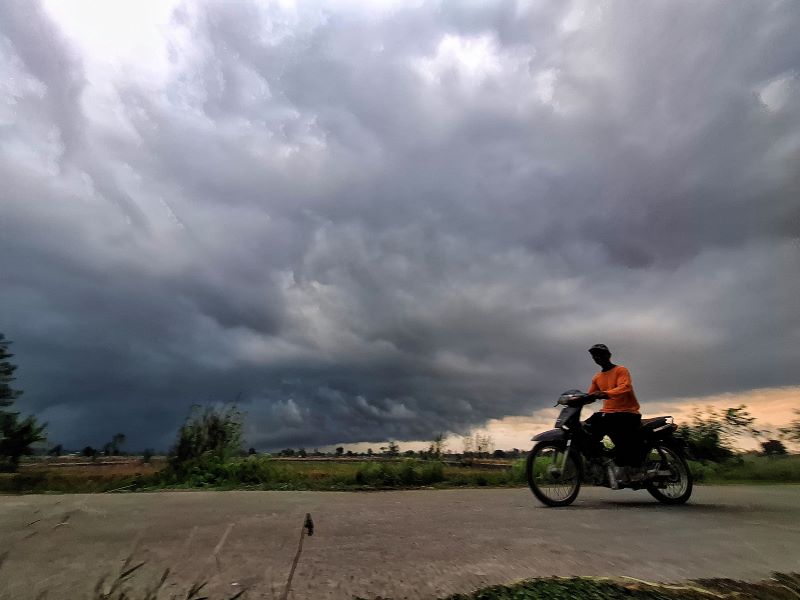 GELAP: Pengendara melintas di bawah awan mendung yang menggelayut di wilayah Kecamatan Dawarblandong, Kabupaten Mojokerto, kemarin (21/10) sore.