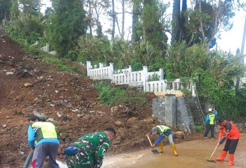 TUTUP JALAN: Petugas membersihkan material longsor di Jalan Desa Claket, Kecamatan Pacet, kemarin (24/10).