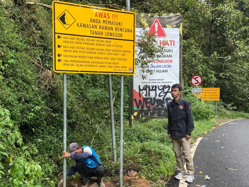 PENCEGAHAN: Petugas BPBD Kabupaten Mojokerto memasang rambu rawan bencana di tepi jalur Pacet-Cangar, Kematan Pacet.